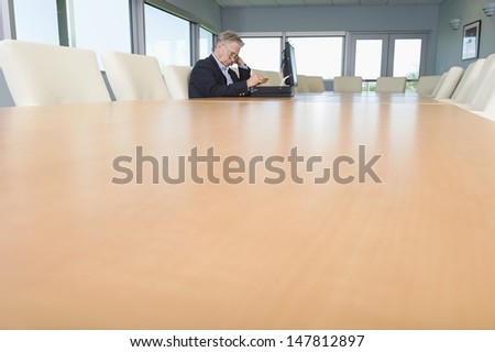 Side view of a serious mature businessman with open briefcase at conference table