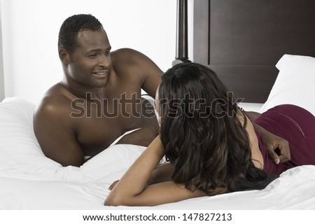 Smiling African American man looking at woman in bed