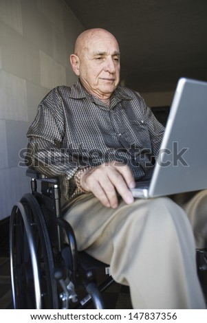 Elderly man using laptop in wheelchair