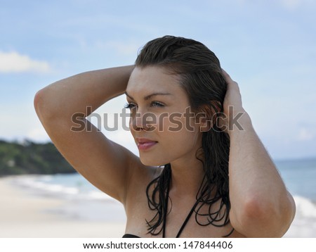 Closeup of a beautiful young woman with hands in hair at beach