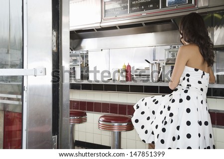 Side view of a young woman sitting at the diner counter