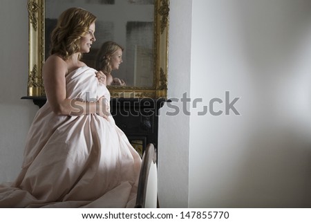 Side view of a thoughtful woman covering herself with quilt at home