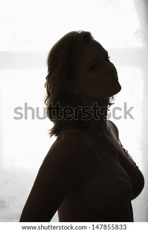 Side view of a silhouette semi dressed woman against curtain