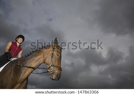 Low angle view of a female horseback rider sitting on brown horse