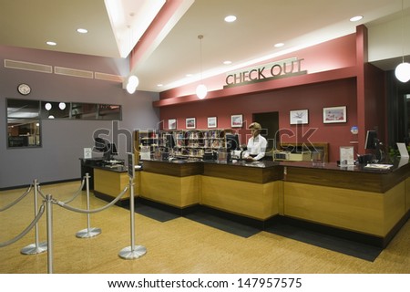 View Of A Female Library Staff Standing At Checkout Counter In Library