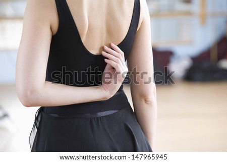 Midsection rear view of ballerina practicing in rehearsal room