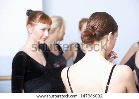 Rear view of woman with classmates standing in ballet rehearsal room