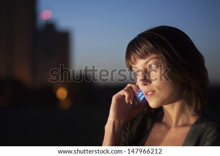 Beautiful young woman using cell phone outdoors at night