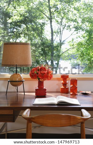 Open book; lamp and retro ornaments on wooden desk by window