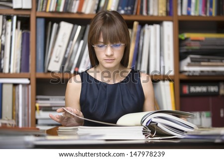 Young female designer going through documents in library