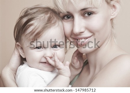 Closeup portrait of happy mother holding baby girl over colored background