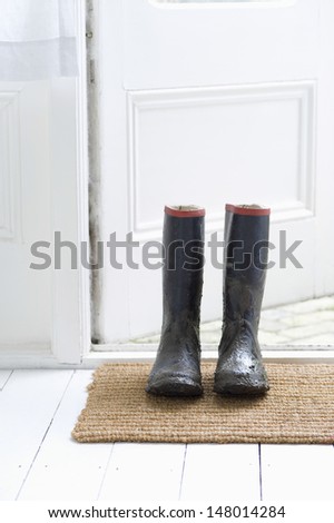 Muddy wellington boots on door mat