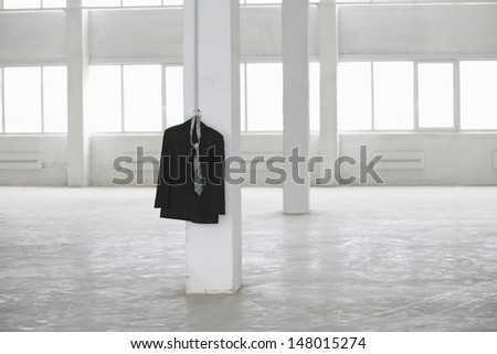 Necktie and suit jacket hanging on pillar in empty warehouse
