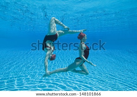 Full Length Side View Of Two Synchronized Swimmers Performing Underwater