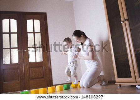 Full length of mother helping son walking on cubes at home