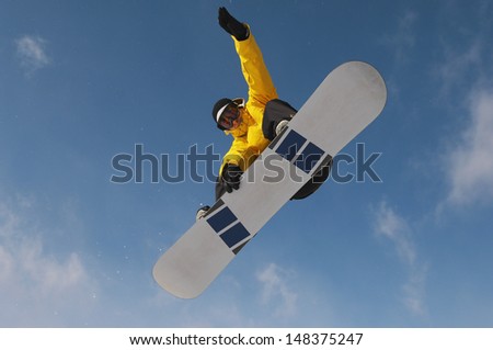 Low angle view of male snowboarder in winter clothes jumping against sky