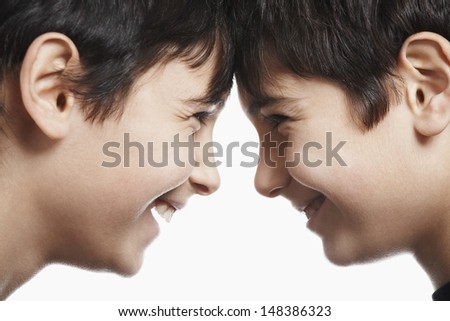 Side view closeup of happy preadolescent siblings with head to head isolated over white background