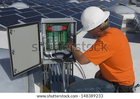 Electrical engineer repairing electricity box at solar power plant