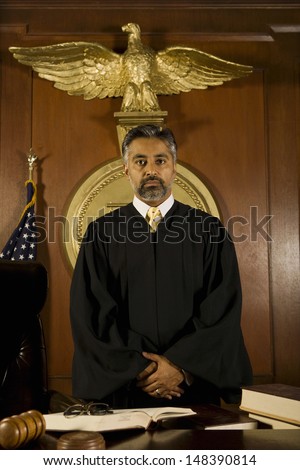 Portrait of middle age male judge standing at table in court room