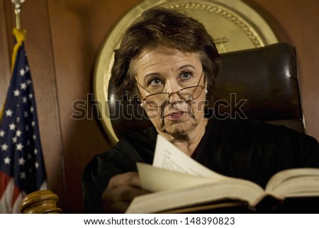 Middle age female judge with book looking away in court room