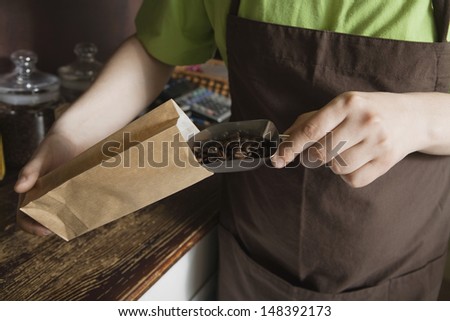 Midsection of saleswoman packing coffee beans in shop