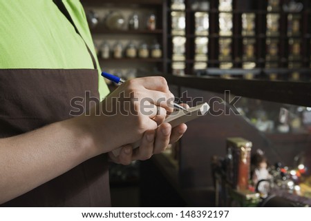 Cropped image of saleswoman writing order in book at tea shop