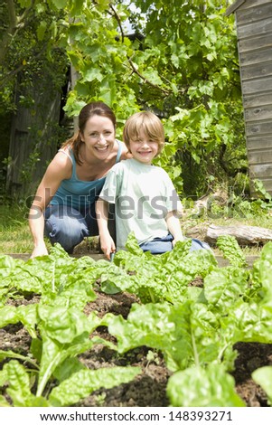Portrait of happy mother and son gardening together in an allotment