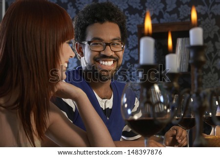 Smiling young couple looking at each other at dinner party