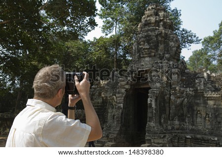 Rear view of middle aged man photographing ancient temple
