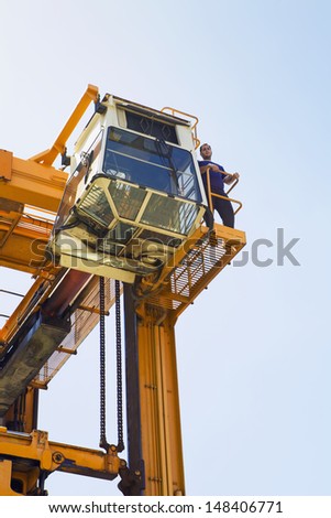 Operator having a break on gantry of mobile crane against clear sky at Limassol Cyprus