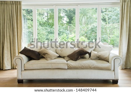 Comfy sofa with cushions against glass windows in the living room
