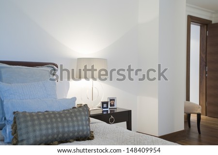 Framed photographs and lamp on side table in bedroom