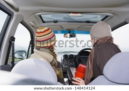 Rear view of young couple wearing warm clothing in car during road trip