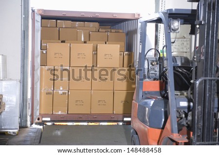 Cardboard boxes and fork lift truck in distribution warehouse