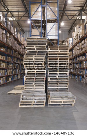 Wooden pallets and cardboard boxes stacked in distribution warehouse