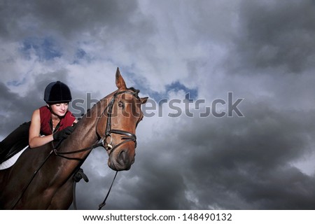 Low angle view of a female jockey riding on brown horse