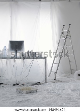 Desk and computer covered in transparent dust sheets in preparation for decoration