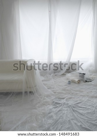 Empty room covered in dust sheets prepared for painting and decorating