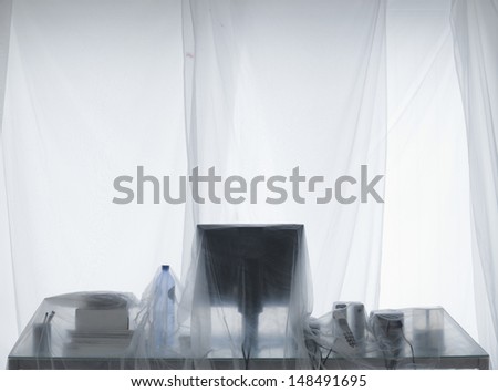 Desk and computer covered in transparent dust sheets in preparation for decoration