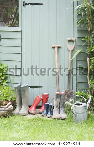 Spades; rake; wellington boots by garden shed