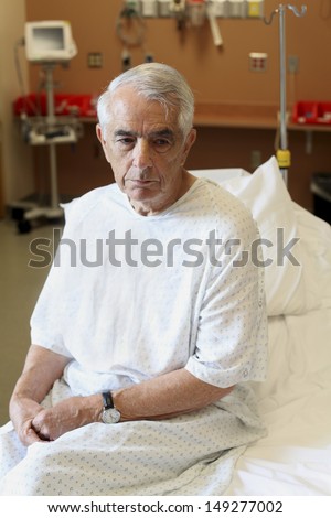 Unhappy elderly man sitting on hospital bed
