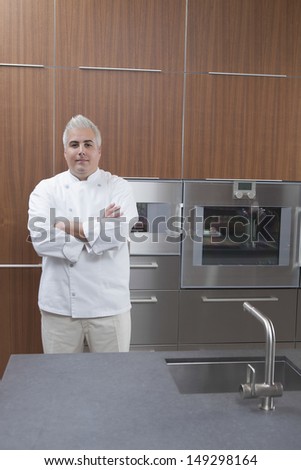 Portrait of confident male chef with arms crossed in commercial kitchen