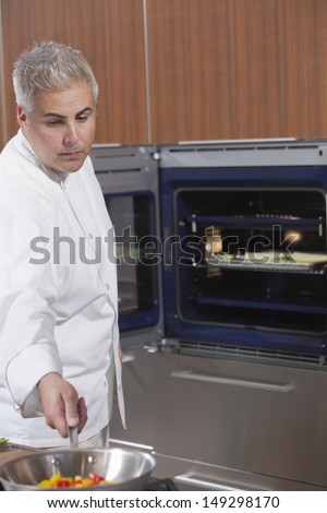 Male chef cooking vegetables in work pan at kitchen