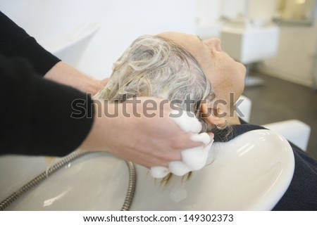Senior woman getting hair washed by hairstylist in parlor
