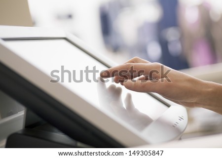 Closeup of woman\'s hand touching screen of cash register in store
