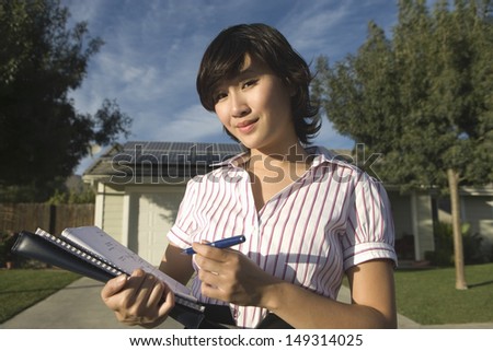 Portrait of young female solar panel worker working on blueprint outdoors