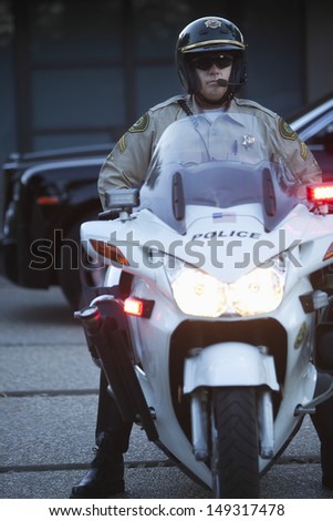Full length of middle aged policeman wearing helmet while sitting on motorbike