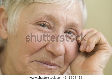 Closeup portrait of elderly woman smiling against beige background
