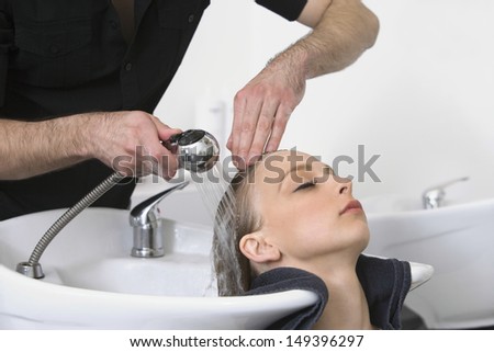 Closeup of young woman getting hair wash from hairdresser in salon