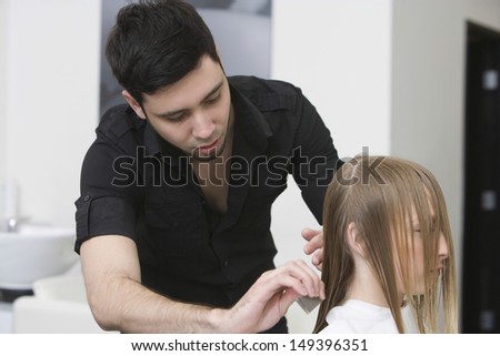 Male hairdresser combing client\'s hair before haircut at beauty parlor